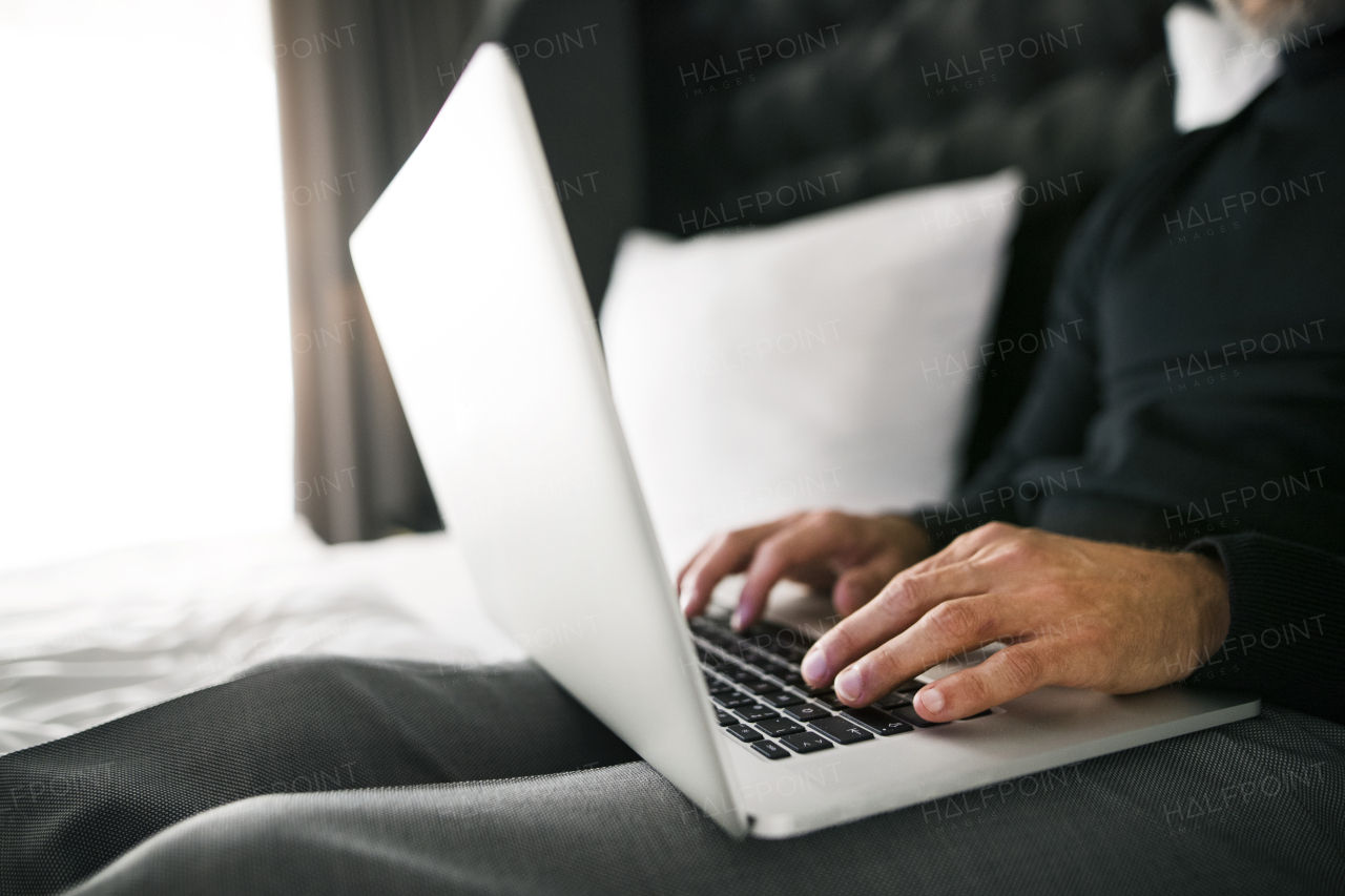 Unrecognizable businessman with laptop in a hotel room. Handsome man working on computer. Close up.