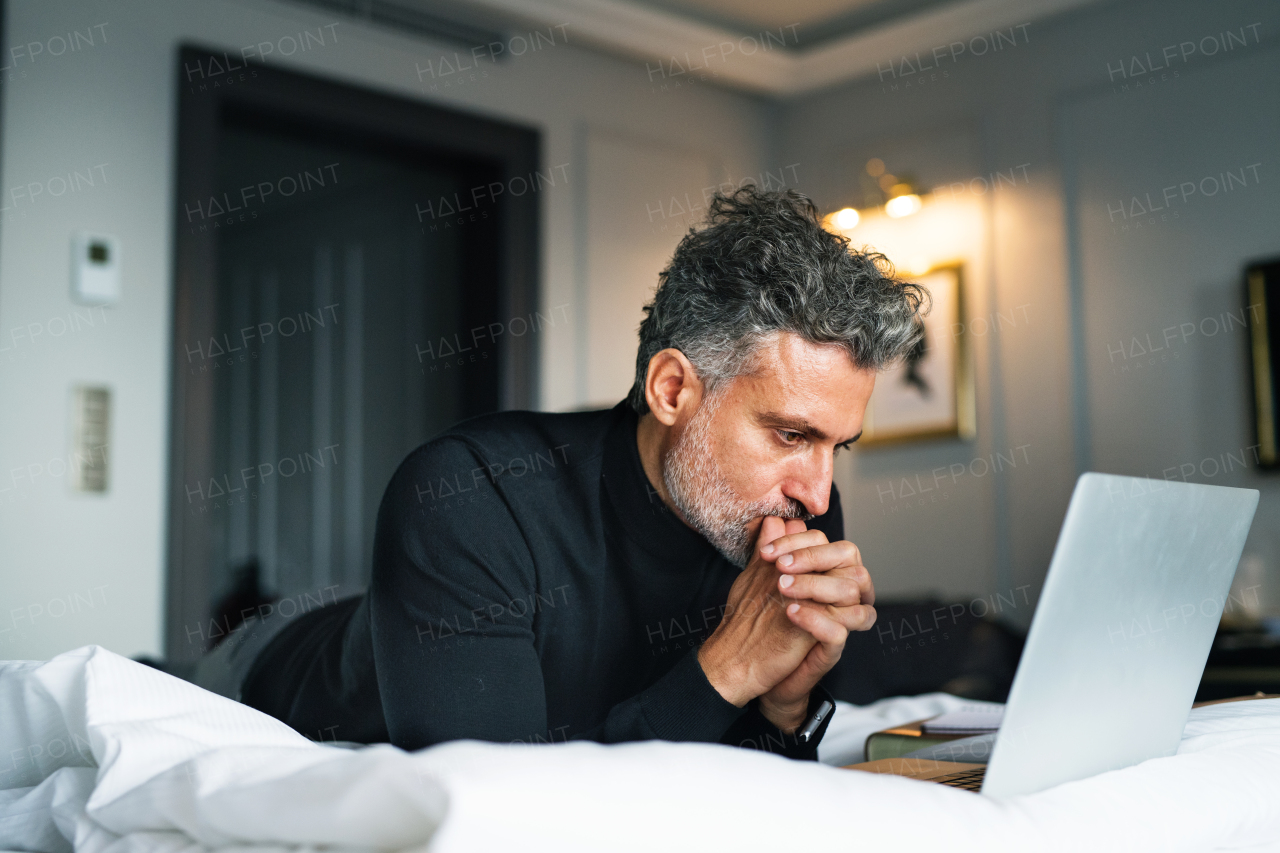 Mature businessman with laptop in a hotel room. Handsome man working on computer.