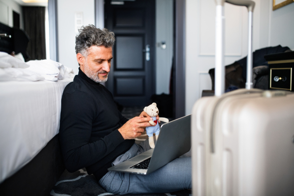 Unrecognizable businessman with laptop in a hotel room. Handsome man using online phone call and video.