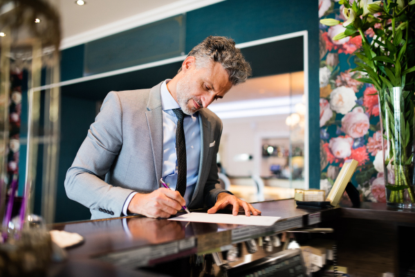 Mature businessman checking in at hotel reception.