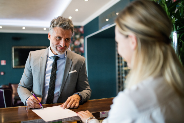 Mature businessman checking in at hotel reception.