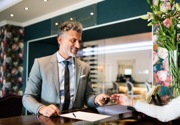 Mature businessman checking in at hotel reception.