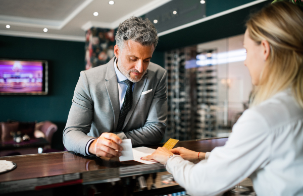 Mature businessman checking in at hotel reception.