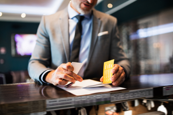 Unrecognizable mature businessman checking in at hotel reception.