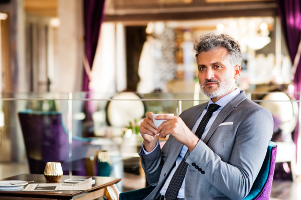 Mature businessman with coffee sitting in a hotel lounge.