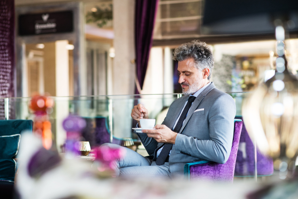 Handsome mature businessman with coffee in a hotel lounge.