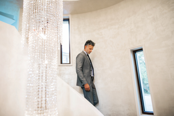 Mature businessman with suitcase walking down the stairs, travelling.