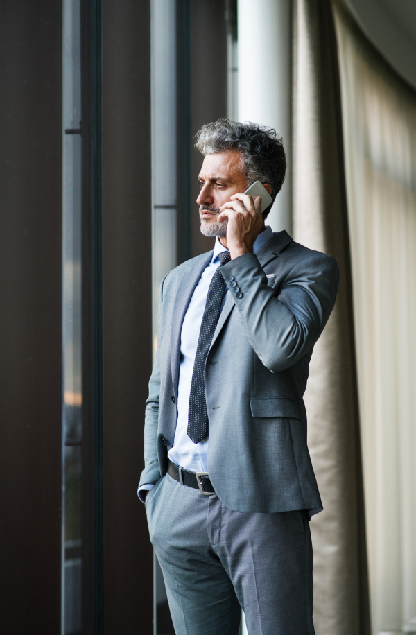 Mature businessman in a hotel with a smartphone. Man making a phone call.