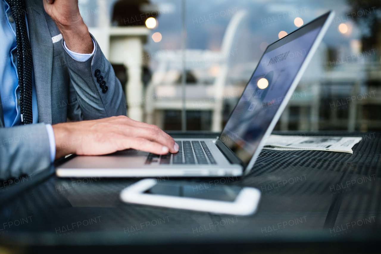 Unrecognizable businessman with laptop sitting in an outdoor hotel cafe.