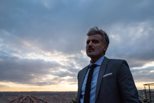 Mature businessman standing in a hotel balcony in the evening.