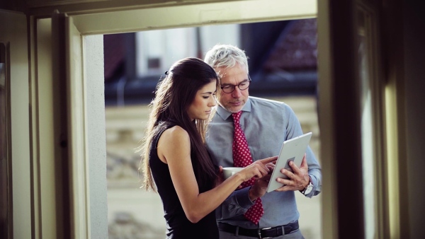 Man and woman business partners with tablet standing on a terrace in office in city, talking. Slow motion.