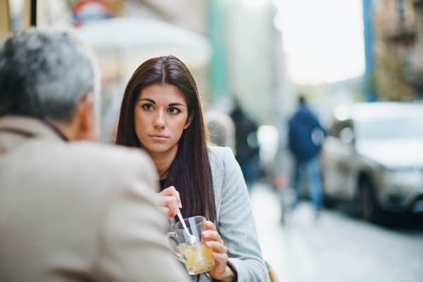 Unrecognizable man and woman business partners with drinks sitting in a cafe in city, talking. Copy space.