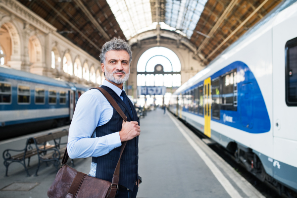 Handsome mature businessman in a city. Man waiting for the train at the railway station.