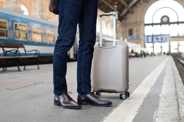 Legs of unrecognizable businessman in a city. Man waiting for the train at the railway station.