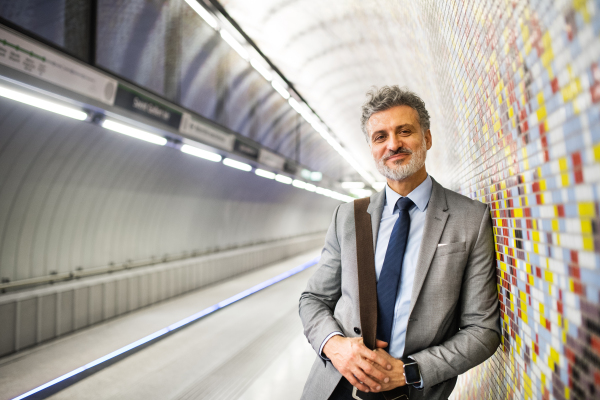 Handsome mature businessman in a city. Man waiting for the train at the subway station.