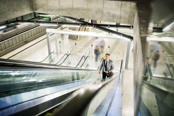 Handsome mature businessman in a city. Man on an escalator at the subway station.