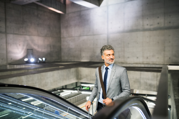 Handsome mature businessman in a city. Man on an escalator at the subway station.