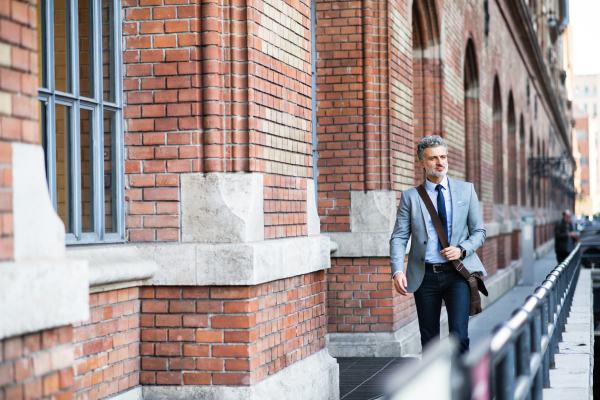 Handsome mature businessman walking in a city.