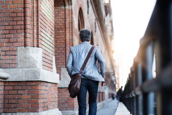 Handsome mature businessman walking in a city. Rear view.