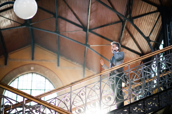 Handsome mature businessman with smartphone in a city. Man walking down the stairs.