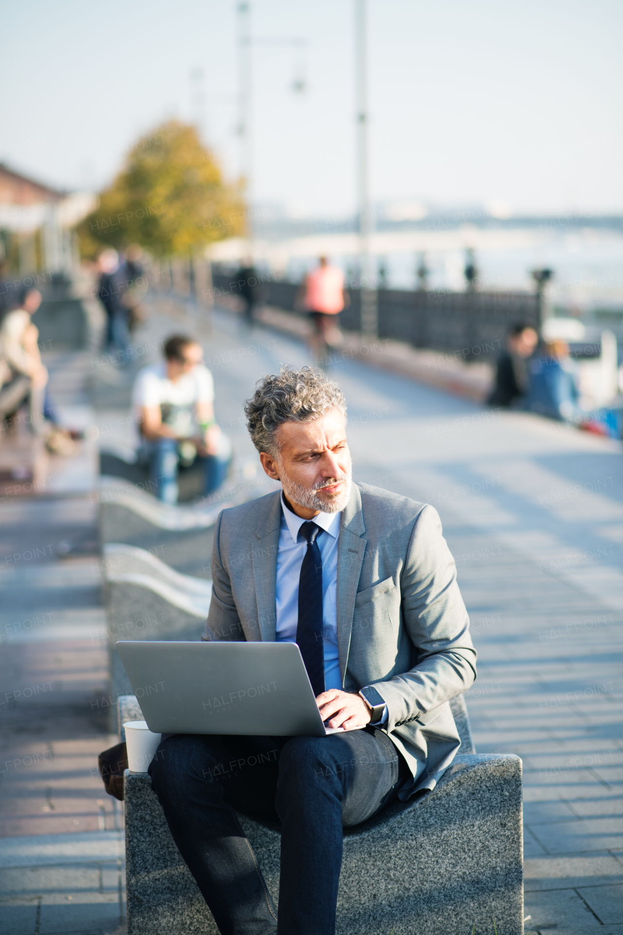 Handsome mature businessman with laptop in a city.