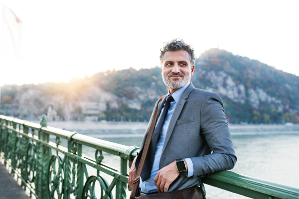 Handsome mature businessman in a city, standing on the bridge.