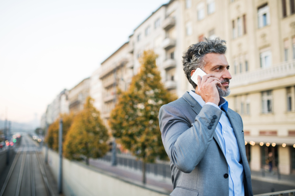 Handsome mature businessman with a smartphone in a city.