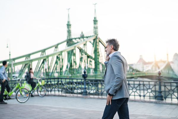 Handsome mature businessman with smartphone in a city. Man making a phone call.