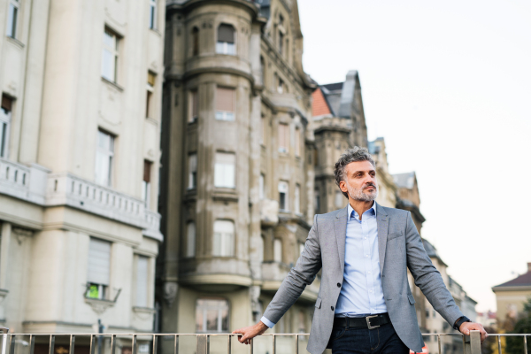 Handsome mature businessman in a city, taking a moment to relax.