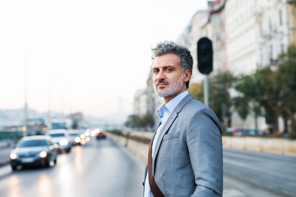 Handsome mature businessman in a city, waiting at the traffic lights.