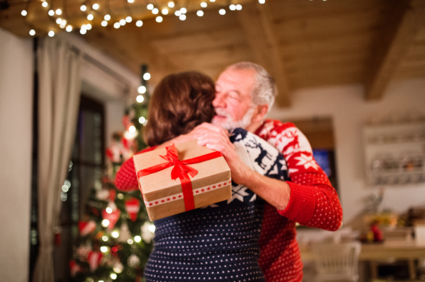 Senior couple a Christmas time. Woman is giving man a Christmas present.