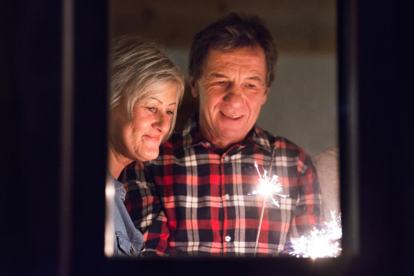 Senior couple with sparklers at Christmas time having fun. Shot through glass.