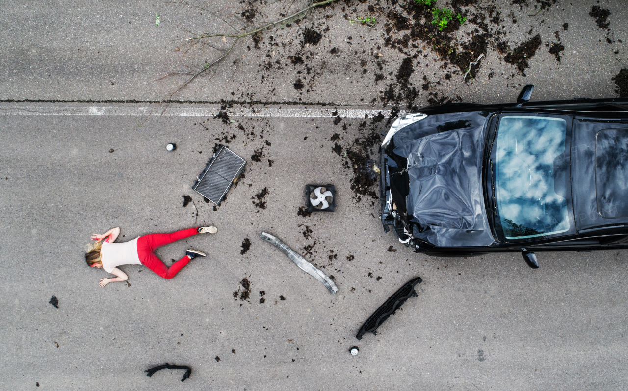 Top view of young injured woman lying in blood on the road, unconscious. A car accident concept. Copy space.