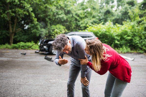 A young woman talking to a mature man after a car accident, helping him.