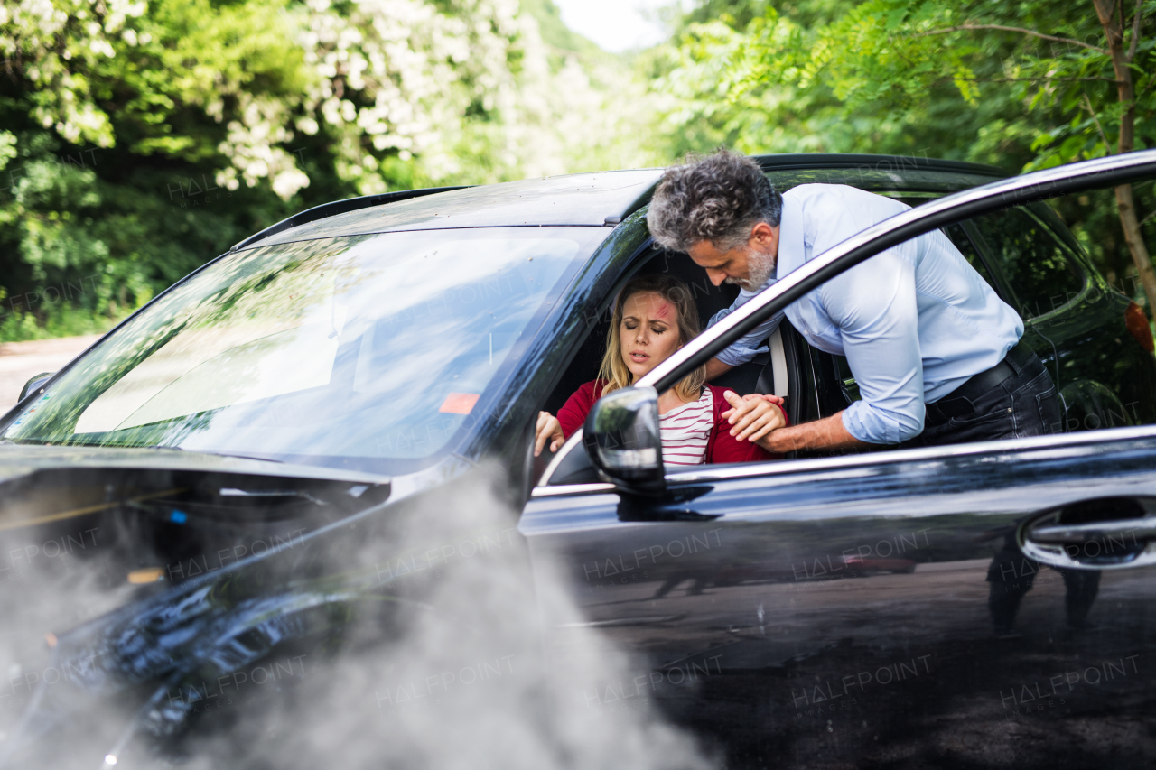 A mature man helping a young woman to get out of the car after a car accident.