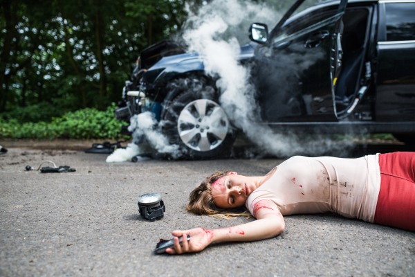 Young injured woman lying on the road, unconscious. A car accident concept. Copy space.