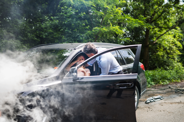 A mature man helping a young woman to get out of the car after a car accident.