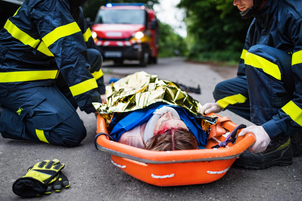 A young injured woman in a plastic stretcher after a car accident, covered by thermal blanket. Close up.