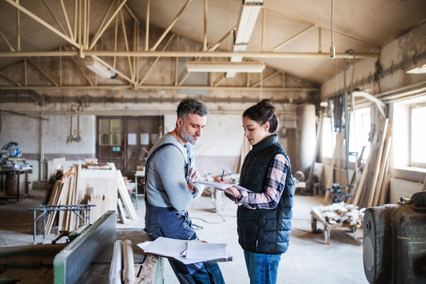 Portrait of a man and woman workers in the carpentry workshop, making plans.