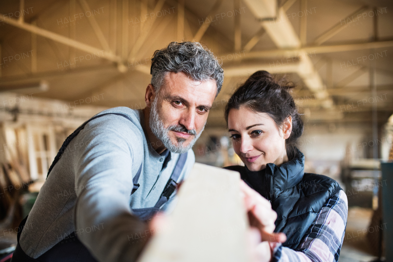 Portrait of a man and woman workers in the carpentry workshop, working together.