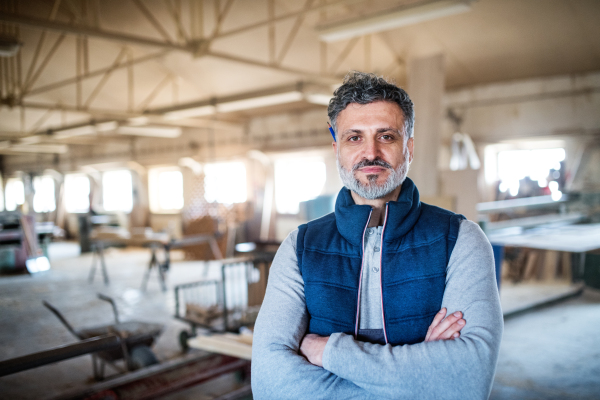 Portrait of a mature man worker in the carpentry workshop, arms crossed. Copy space.