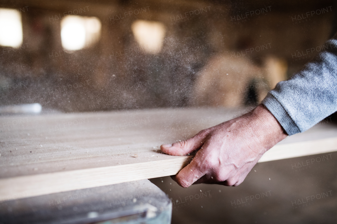 A hand of an unrecognizable man worker in the carpentry workshop, working with wood.