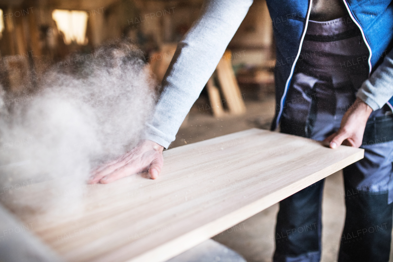 An unrecognizable man worker in the carpentry workshop, working with wood.