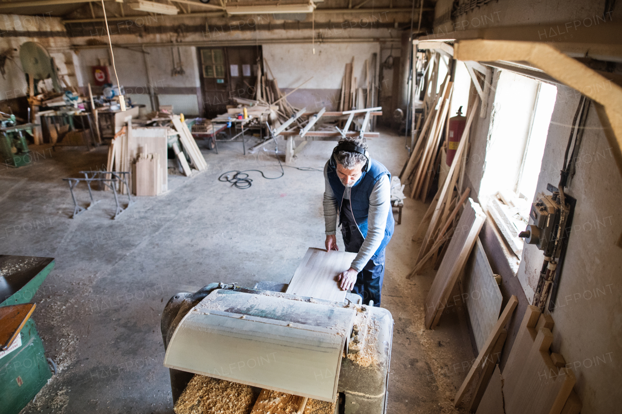 A mature man worker in the carpentry workshop, working with wood. Top view.