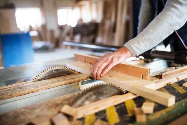 An unrecognizable man worker in the carpentry workshop, working with wood.