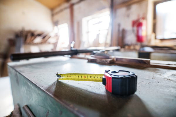 Aflexible ruler in carpentry workshop. Blurred background.