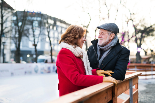 Happy senior couple on a walk in a city in winter, talking.