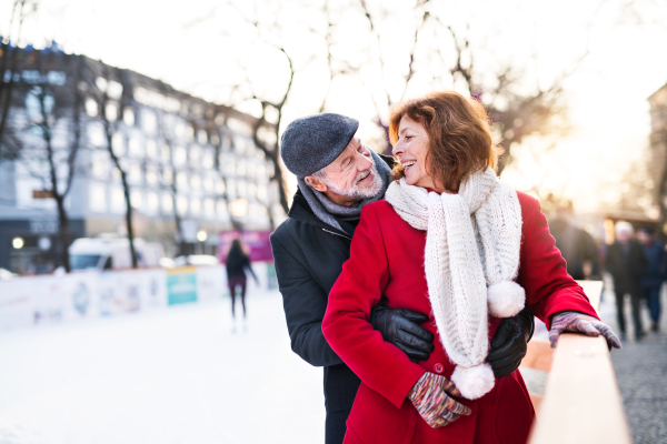 Happy senior couple on a walk in a city in winter, hugging.