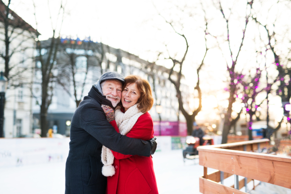 Happy senior couple on a walk in a city in winter, hugging.