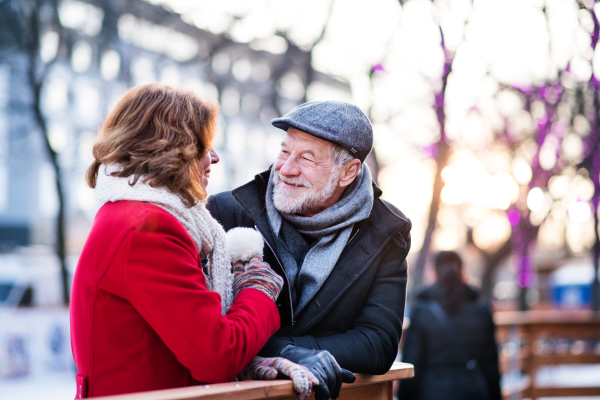 Happy senior couple on a walk in a city in winter, hugging.